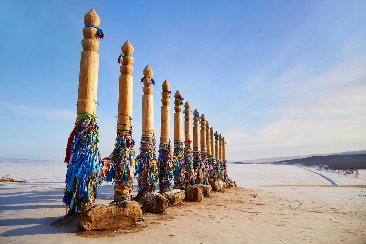 Деревянные ритуальные столбы с разноцветными лентами на скале Шаманка