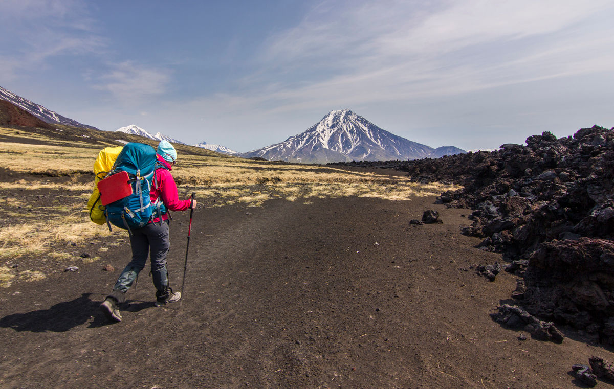 Турист в походе на фоне снежных вулканов Камчатки