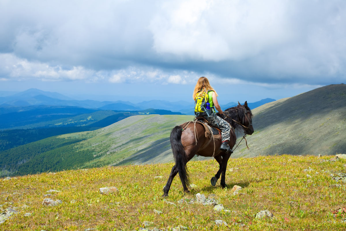 Девушка верхом на лошади в горах Алтая
