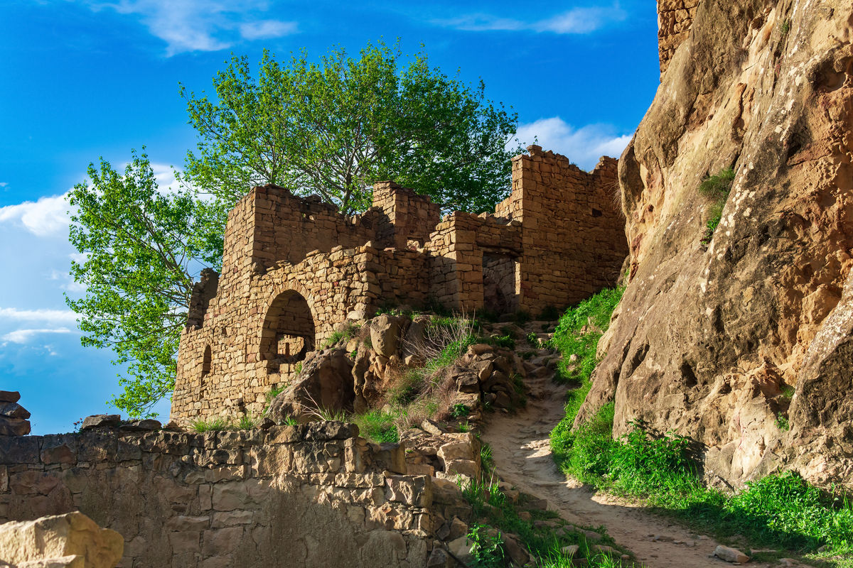 Руины стен домов на скале в заброшенной деревне Гамсутль