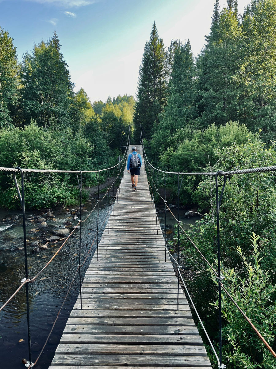 Мужчина идет по мосту в парке Таганай