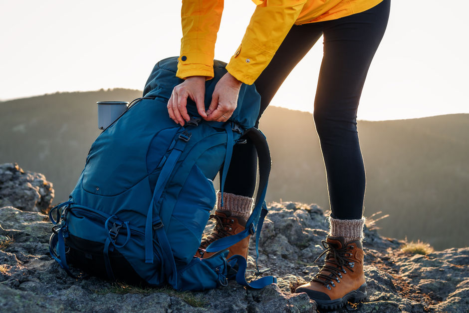 Женщина открывает рюкзак после восхождения на горную вершину