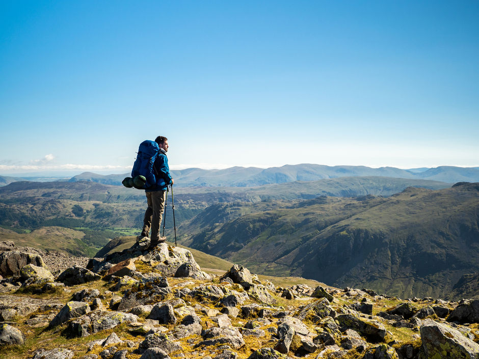 Путешественник смотрит на пейзаж с вершины горы