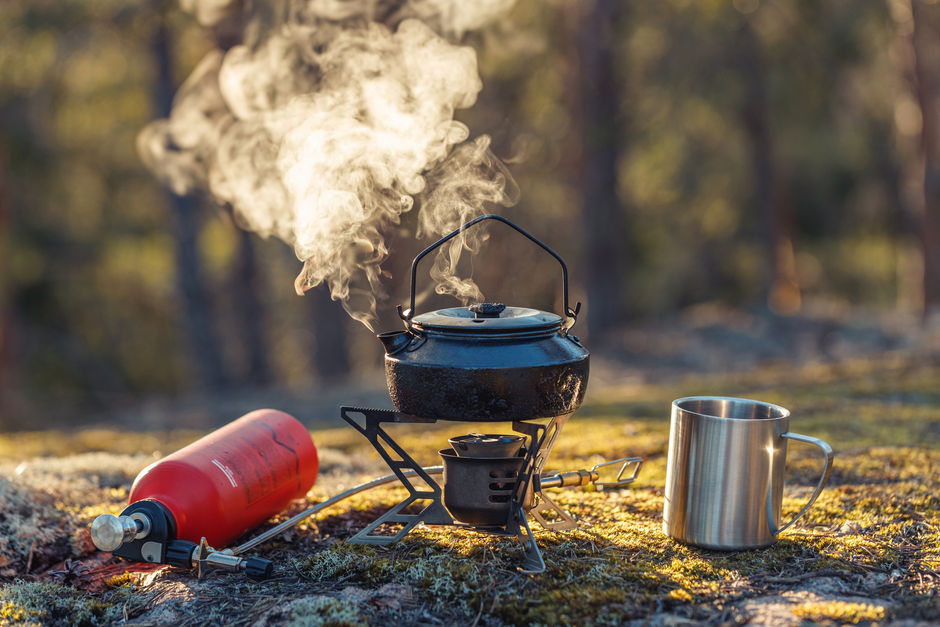 Кипячение чайника на многотопливной горелке с кружкой в лесу